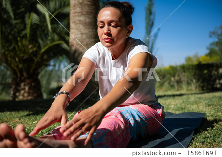 Woman doing yoga stretches outdoors in a sunny park Woman doing yoga stretches outdoors in a sunny park 115861691