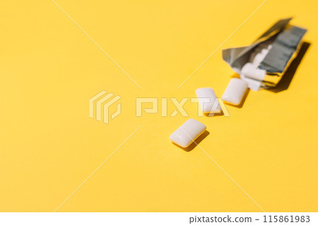Chewing gum pads spilled out of a foil package on a yellow background Chewing gum pads spilled out of a foil package on a yellow background 115861983