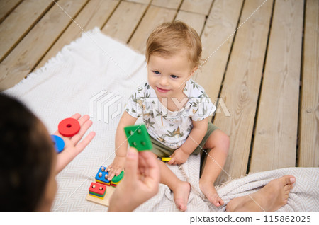 Toddler playing with educational toys on wooden deck Toddler playing with educational toys on wooden deck 115862025