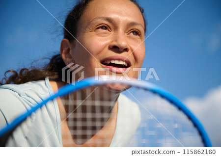 Close-up of a multi ethnic smiling young active woman playing tennis on a sunny day 115862180