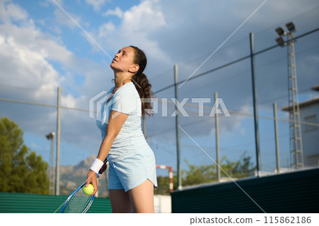 Woman playing tennis on outdoor court ready to serve 115862186
