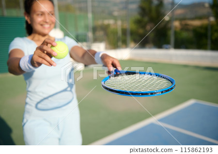 Woman in her 40s playing tennis on the court with a focus on the ball and racket Woman in her 40s playing tennis on the court with a focus on the ball and racket 115862193