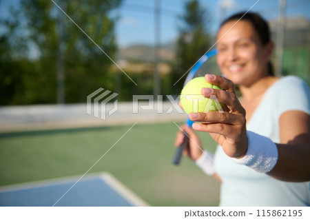Smiling woman in her 40s playing tennis outdoors on a sunny day 115862195