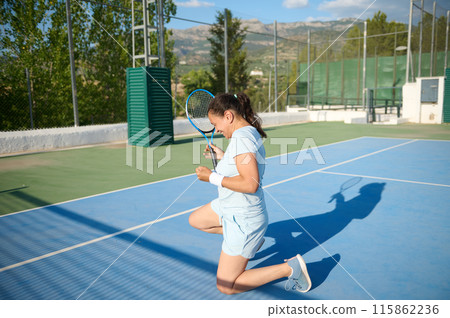 Woman in her 40s playing tennis on outdoor court, celebrating a score Woman in her 40s playing tennis on outdoor court, celebrating a score 115862236