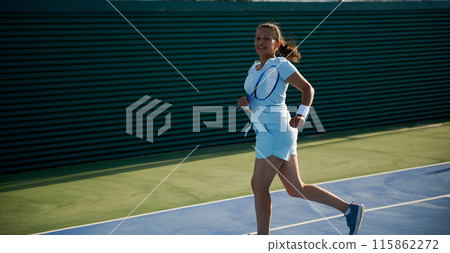 Woman in her 40s playing tennis on court in athletic wear and smiling 115862272