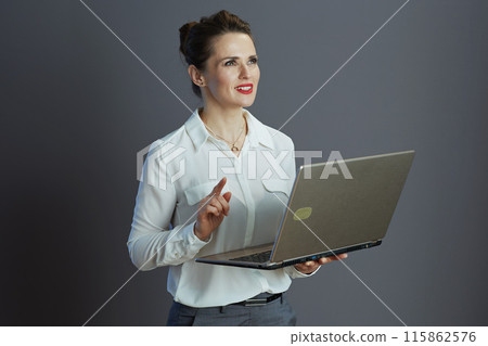 pensive stylish woman worker using laptop against grey 115862576