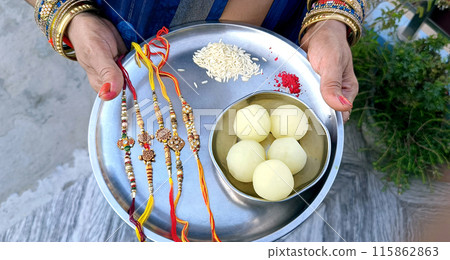 Indian Sister holding a plate of rakhi and sweets on the occasion of Raksha Bandhan 115862863