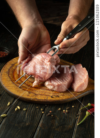 Cooking steak meat by hands of chef for barbecue. Raw beef meat on kitchen vintage table with spices. Place for advertising 115862889