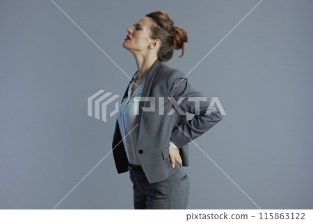 stressed woman employee having back pain isolated on grey stressed woman employee having back pain isolated on grey 115863122