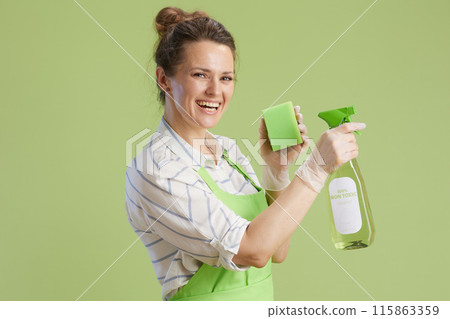 smiling woman in green apron and rubber gloves against green smiling woman in green apron and rubber gloves against green 115863359