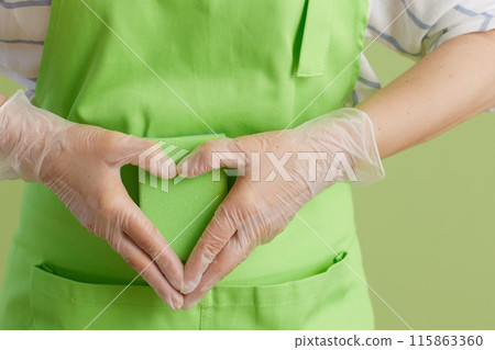 Modern woman showing heart hands isolated on green 115863360
