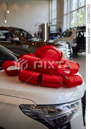 An iconic new car is being presented with a ribbon bow at the showroom for a celebratory event 115863703