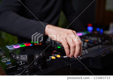 control DJ for mixing music with blurred people dancing at party in nightclub. 115863715
