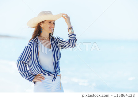 smiling stylish 40 years old woman on beach with straw hat smiling stylish 40 years old woman on beach with straw hat 115864128