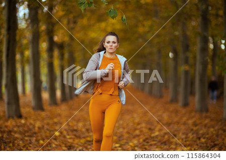 stylish woman in fitness clothes in park running 115864304