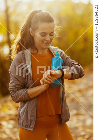 smiling elegant woman in fitness clothes in park 115864323