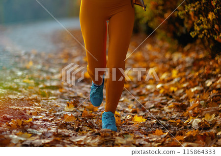 Closeup on woman in fitness clothes in park running Closeup on woman in fitness clothes in park running 115864333