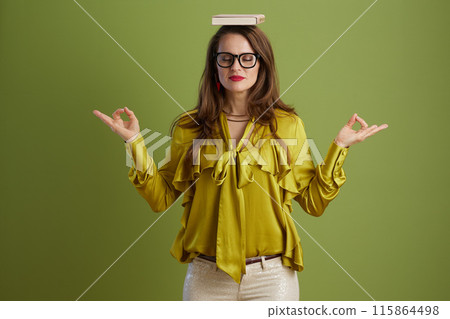 relaxed woman in green blouse and glasses meditating on green relaxed woman in green blouse and glasses meditating on green 115864498