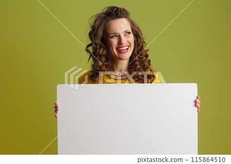 happy fit woman showing blank board against green background 115864510