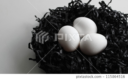 Three White Eggs In A Nest Made With Black Shavings On White At A Side Of The Image 115864516