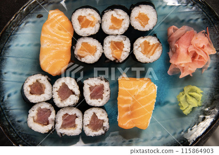 Top view of traditional japanese cuisine . Sushi rolls set with salmon , tuna fish and vegetable served on black stone table . Asian food on black stone slate with chopsticks . Top view of traditional japanese cuisine . Sushi rolls set with salmon , tuna fish and vegetable served on black stone table . Asian food on black stone slate with chopsticks . 115864903
