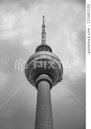 The Berlin TV Tower stands tall, piercing a dramatic, cloud-filled sky above Germany capital. 115865320
