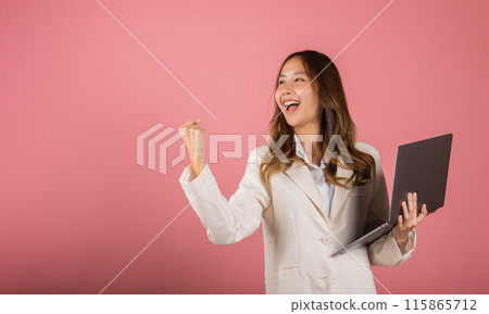 Portrait of happy Asian beautiful business woman teen confident smiling face holding using laptop computer and excited celebrating success, studio shot isolated on pink background, with copy space 115865712