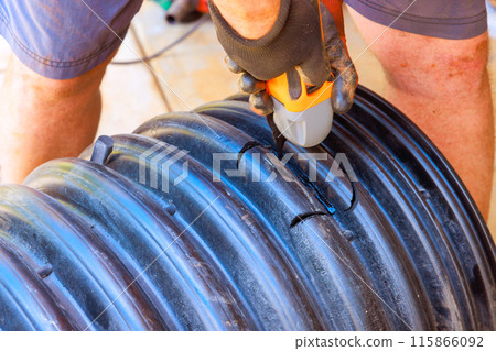 Drilling hole in black plastic polypropylene sanitary pipe in order to connect it to another pipe Drilling hole in black plastic polypropylene sanitary pipe in order to connect it to another pipe 115866092