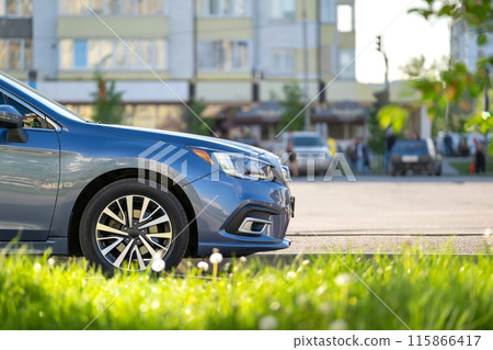 Car parked on a city street side with blurred urban traffic. 115866417