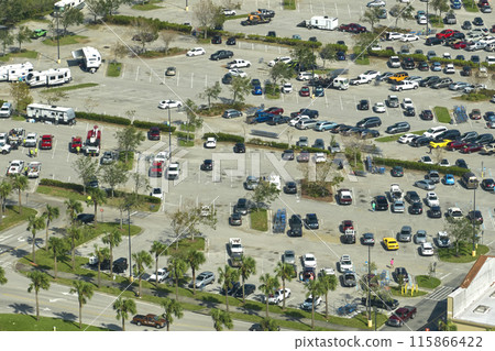 Aerial view of large parking lot with many parked colorful cars. Carpark at supercenter shopping mall with lines and markings for vehicle places and directions Aerial view of large parking lot with many parked colorful cars. Carpark at supercenter shopping mall with lines and markings for vehicle places and directions 115866422