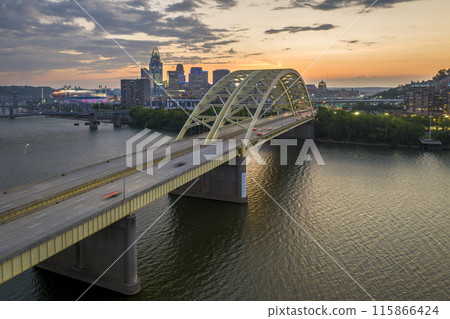 Downtown district of Cincinnati city in Ohio, USA at night with driving cars traffic on Daniel Carter Beard Bridge and brightly illuminated high skyscraper buildings. American travel destination 115866424
