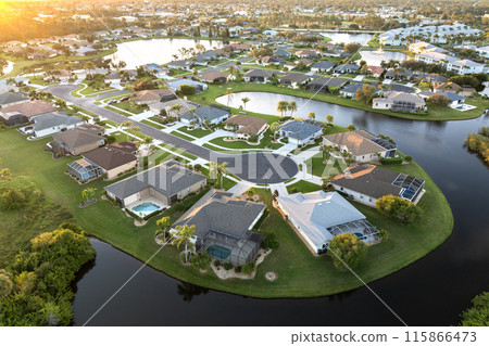 Cul de sac street dead end at sunset and private residential houses in rural suburban sprawl area in North Port, Florida. Upscale suburban homes with large waterfront backyards 115866473