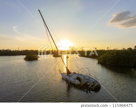 Aerial view of sunken sailboat on shallow bay waters after hurricane in Manasota, Florida 115866475