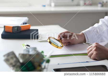 The doctor is looking over a document with a magnifying glass . The doctor is looking over a document with a magnifying glass . 115866660