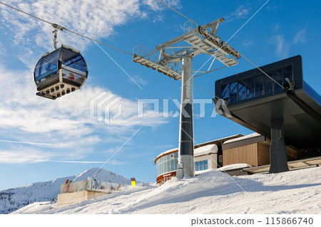 Ski lift gondola cable car station operates in luxury alpine ski resort on a snowy winter day with mountain background and a clear blue sky. Serfaus-Fiss-Ladis Alps winter resort region 115866740
