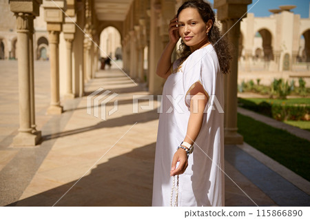 Woman in white dress posing in architectural columned walkway on a sunny day Woman in white dress posing in architectural columned walkway on a sunny day 115866890