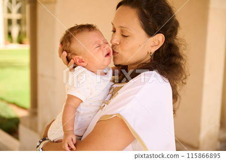 Mother comforting crying baby outdoors in sunny setting 115866895