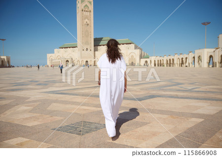 Person in traditional white clothing walking towards Hassan II Mosque under clear blue sky Person in traditional white clothing walking towards Hassan II Mosque under clear blue sky 115866908
