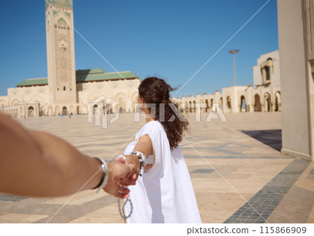 Woman leading the way towards historic mosque on a sunny day Woman leading the way towards historic mosque on a sunny day 115866909