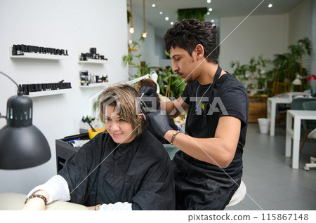 Hair stylist working on woman's hair in beauty salon 115867148