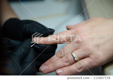 Manicure session in a beauty salon with gloved hands 115867158