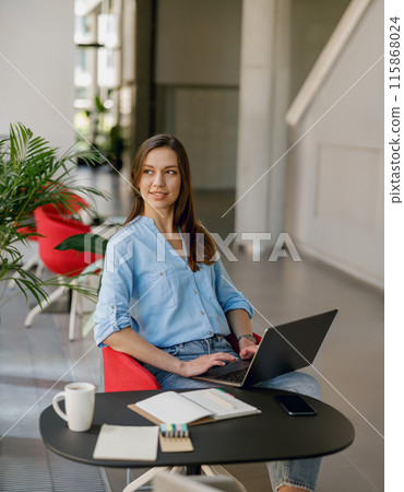 A young professional woman is working on a laptop in a sleek modern office space A young professional woman is working on a laptop in a sleek modern office space 115868024