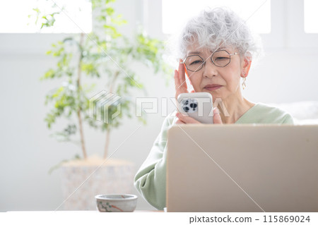 Smiling senior woman holding a smartphone (smartphone) Having difficulty seeing the smartphone due to presbyopia 115869024