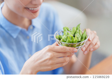 A woman eating edamame as a snack 115869220