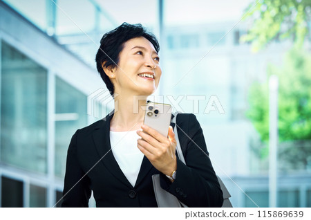 穿著西裝的中層女商人站著智能手機 穿著西裝的中層女商人站著智能手機 115869639