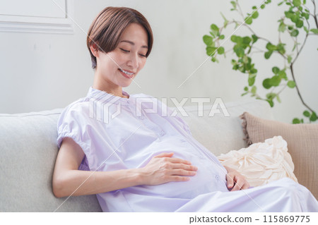 A pregnant woman touching her belly with a smile A pregnant woman touching her belly with a smile 115869775