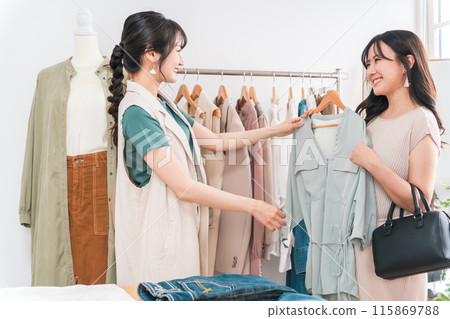 A woman and a shop clerk shopping for clothes at an apparel shop A woman and a shop clerk shopping for clothes at an apparel shop 115869788