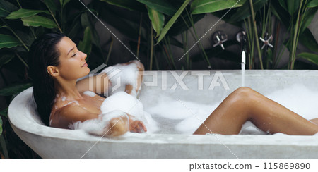 Woman Relaxing in Bubble Bath in Tropical Outdoor Setting 115869890