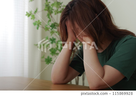 A woman in her 40s holding her head A woman in her 40s holding her head 115869928