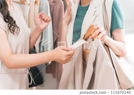 A woman checking the price of a jacket or outerwear at an apparel shop (good value/bargain) A woman checking the price of a jacket or outerwear at an apparel shop (good value/bargain) 115870140